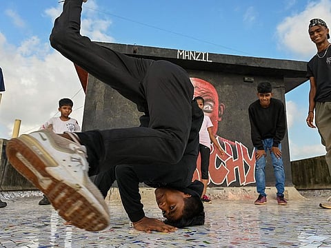 A student perform during a group class to learn breaking or 'b-boying' at a training session on the rooftop of a building in Dharavi slums in Mumbai.