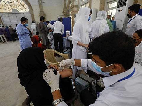 A resident receives a dose of  COVID-19 vaccine at a vaccination facility in Karachi.