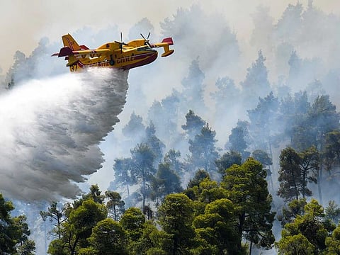 A firefighting airplane makes a water drop as a wildfire burns near the village of Ellinika, on the island of Evia, Greece, August 8, 2021.