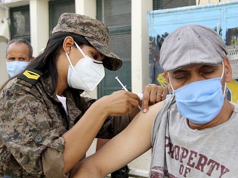 A soldier administrates a COVID-19 vaccine to a man at the Assad ibin El Fourat school in Oued Ellil, outside Tunis, on August 8, 2021.