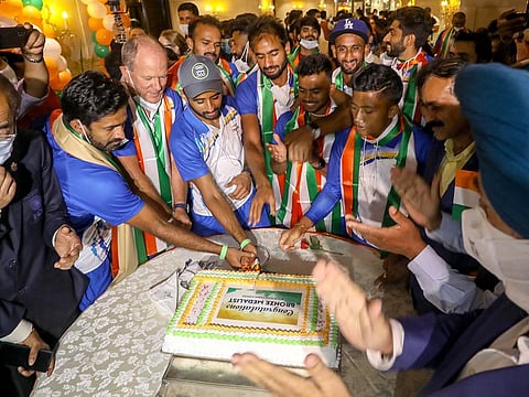 Members of Indian men's hockey team, which finished with a bronze medal in Tokyo Olympics, celebrate by cutting a cake on their homecoming in a New Delhi hotel on Monday.
