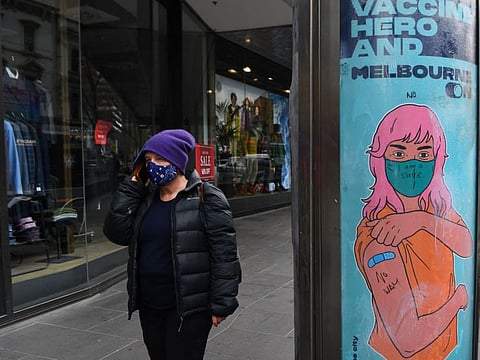 A person walks past a graffited sign which encourages people to get vaccinated in Melbourne's central business district on August 11, 2021.