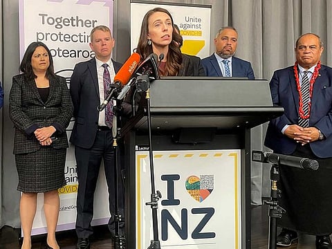Flanked by lawmakers, New Zealand Prime Minister Jacinda Ardern delivers a speech on Thursday, Aug. 12, 2021, in Wellington, New Zealand. Ardern announced plans to begin a cautious reopening of New Zealand's borders to international travelers from early next year.