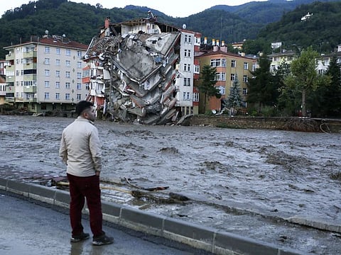 A man looks on as flood waters sweep by in Bozkurt town of Kastamonu province of Turkey, on August 12, 2021. The floods triggered by torrential rains battered the Black Sea coastal provinces of Bartin, Kastamonu, Sinop and Samsun on Wednesday, demolishing homes and bridges and sweeping cars away by torrents. Helicopters scrambled to rescue people stranded on rooftops.