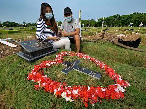 Tirsa Manitik, left, and Erik Alexander visiting the grave of their baby who tested positive for COVID-19 coronavirus before she died, at the Tegal Alur cemetery in Jakarta.