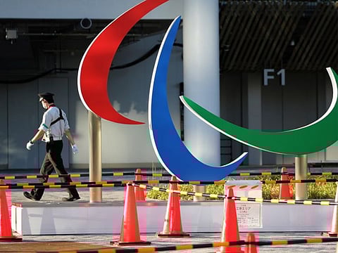 A security guard wearing a protective mask, amid the coronavirus disease outbreak, walks past the symbol of the Paralympic Games under installation at the National Stadium, the main venue of the Tokyo 2020 Olympic and Paralympic Games in Tokyo, Japan.