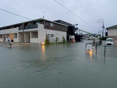 A person stands at a flooded street during heavy rain in Kurume, Fukuoka Prefecture, Japan August 14, 2021, in this still image taken from video provided on social media.