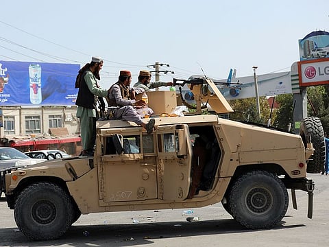 Taliban fighters stand guard in front of the Hamid Karzai International Airport, in Kabul, Afghanistan
