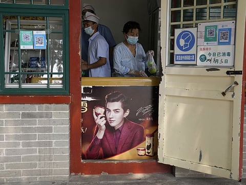 Food vendors work behind an ice cream fridge with an advertisement featuring Chinese-Canadian pop star Kris Wu in Beijing on Tuesday, Aug. 3, 2021. Wu was arrested Monday, Aug. 16, 2021 on suspicion of rape in a high-profile case that followed accusations the singer had sex with a 17-year-old while she was drunk and lured young women into sexual relationships.