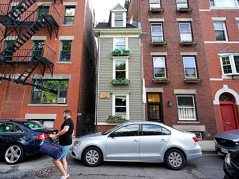 A man walks by Boston's famous Skinny House.
