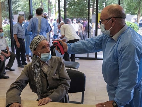 An Iraqi medic checks an elderly man's temperature as he arrives to receive the Astrazeneca COVID-19 vaccine at an inoculation centre in Arbil, the capital of the autonomous Kurdish region of northern Iraq, on August 7, 2021. Repeated Turkish raids have stoked tensions with Baghdad, but President Recep Tayyip Erdogan has warned that his country will deal with the PKK presence if Iraq is unable to do so.