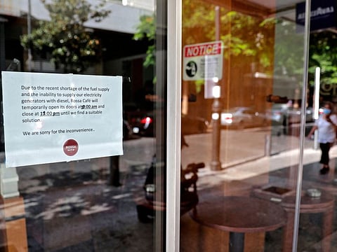 A picture shows a sign, which informs customers about the reduced working hours, placed on the doors of a coffee shop in Beirut's Hamra district on August 20, 2021, as Lebanon battles endless power cuts. Both the Americans and Iranians are racing to win hearts in Lebanon, as the population struggles to make ends meet.