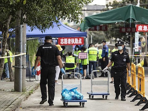 Security guards help transport deliveries of food and other necessities from couriers to residents of a neighbourhood placed under lockdown, after a resident recently tested positive for Covid-19, in Shanghai, China, on Saturday, Aug. 21, 2021.