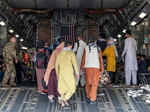 In this image courtesy of the US Air Force, a US Air Force loadmaster, assigned to the 816th Expeditionary Airlift Squadron, assists evacuees aboard a C-17 Globemaster III aircraft in support of Operation Allies Refuge at Hamid Karzai International Airport (HKIA), Kabul, Afghanistan, on August 20, 2021.