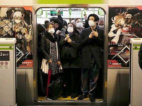 In this March 2, 2020, file photo, commuters wearing masks stand in a packed train at the Shinagawa Station in Tokyo.
