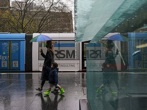 A masked woman with an umbrella walks with a child through the quiet city centre during a lockdown to curb the spread of COVID-19 outbreak in Sydney, Australia, August 24, 2021.