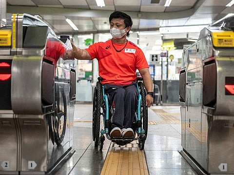 Japanese para-canoeist Masaaki Suwa entering a gate at a train station in Tokyo.