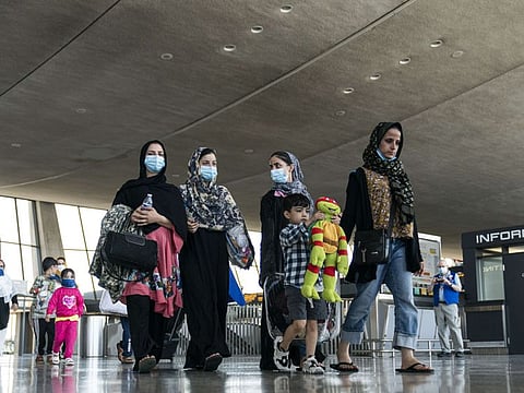 Afghan families walk to a bus that will take them to a refugee processing center at Dulles International Airport on August 24, 2021 in Dulles, Virginia.