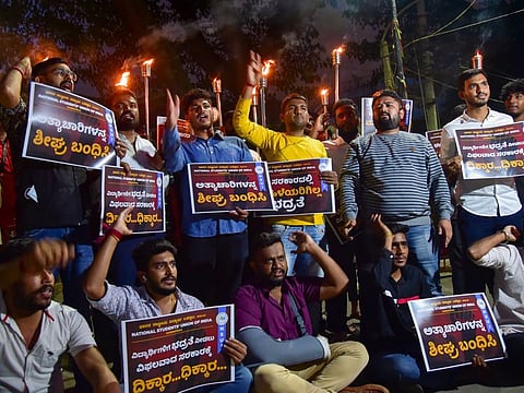 Members of NSUI hold placards and torch light and raise slogans during a protest against the state government's alleged in-action regarding Mysuru gangrape incident, in Bengaluru, on August 26, 2021.