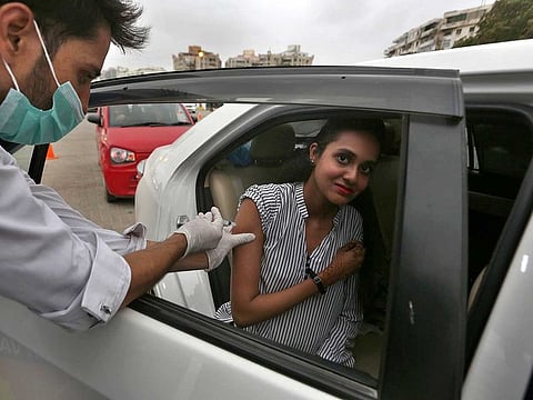 A woman receives the Sinovac COVID-19 vaccine from a health worker at a drive-through vaccination centre, in Karachi in a file photo.