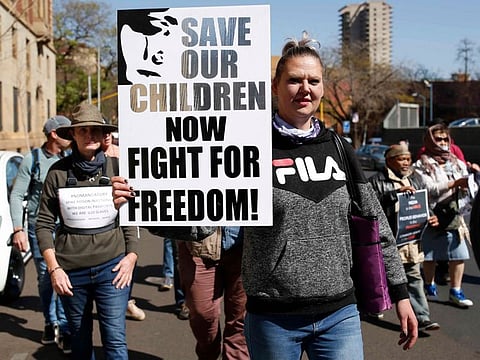 Demonstrators hold up banners and placards during a protest march against vaccinations and wearing of masks, in Pretoria on August 30, 2021.