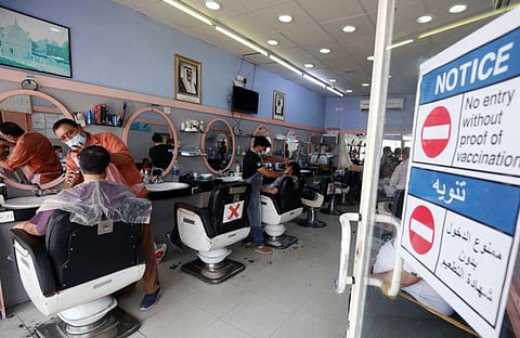 A notice is placed at the entrance to a barber shop in Kuwait City, prohibiting ustomers who are not vaccinated against the coronavirus from entering, on September 3, 2021.