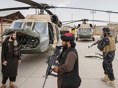 Taliban fighters inventory helicopters damaged by departing American troops at the airport in Kabul, Afghanistan, August 31, 2021.