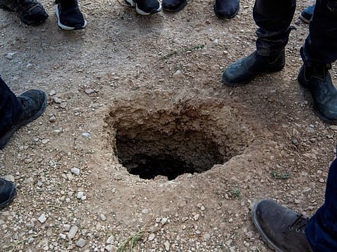 People stand by a hole in the ground outside the walls of Gilboa prison after six Palestinian militants broke out of it in north Israel September 6, 2021.