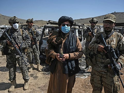 Members of the Taliban Badri 313 military unit stand beside damaged and discarded vehicles parked near the destroyed Central Intelligence Agency (CIA) base in Deh Sabz district northeast of Kabul on September 6, 2021 after the US pulled all its troops out of the country.