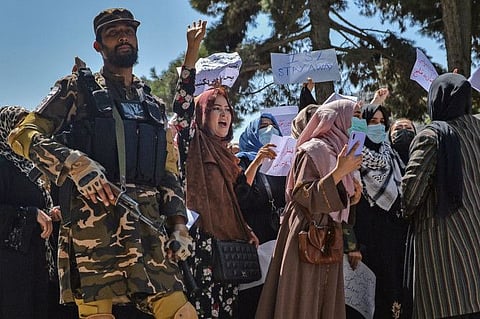 A Taliban fighter stands guard as Afghan women shout slogans during an anti-Pakistan protest rally, near the Pakistan embassy in Kabul, on September 7, 2021.