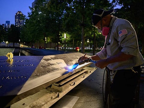 A worker cleans a display showing names of lives lost in the 9/11 terrorist attacks at the 9/11 memorial in New York on September 10, 2021.