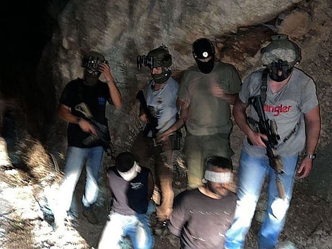 This picture released by the Israeli police on September 11, 2021, shows Zakaria Zubeidi (left) and Mahmoud Ardah, two of the six Palestinians who escaped from a high-security prison earlier this week, blindfolded after being recaptured in the village of Um Al Ghanam near the northern Israeli Arab city of Nazareth.