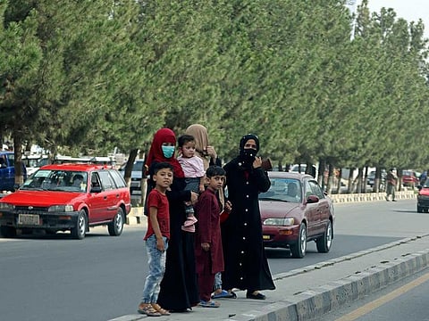 Afghan women along with children stand on a road divider at a street in Kabul on September 12, 2021.