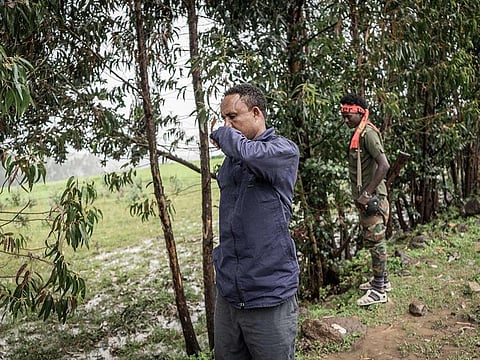 A man covers his nose as he stands near corpses of victims that were killed in an alleged massacre near the village of Chenna, 95 kilometres northeast of the city of Gondar, Ethiopia, on September 14, 2021.
