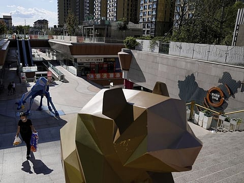A woman walks by a map showing Evergrande development projects in China, at an Evergrande city plaza in Beijing, Harbin has closed a raft of businesses in response, including mahjong halls, cinemas, theatres, karaoke and dance venues, pedicure shops, massage parlors, Internet cafes, gyms and churches and religious sites. on September 21, 2021.