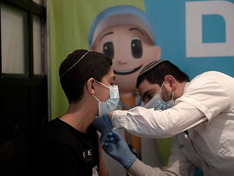 A 14 year-old Israeli receives a booster shot of vaccine at Clalit Health Service’s vaccination centre in the Cinema City complex in Jerusalem.