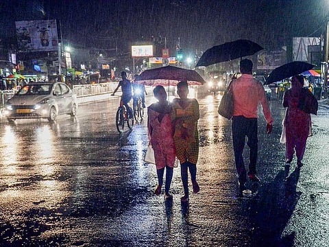 Commuters walk on the street amid rain in Ranchi, Sunday, Sept. 26, 2021.