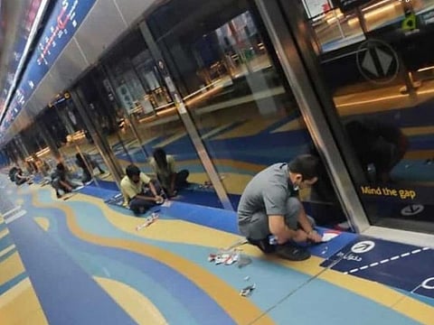 Workers removing the social distancing stickers at the Burjuman Metro station in Dubai on Monday.