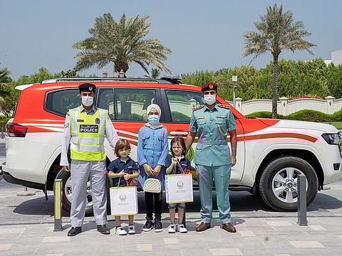The three Syrian siblings with Ajman Police officials after their treat.