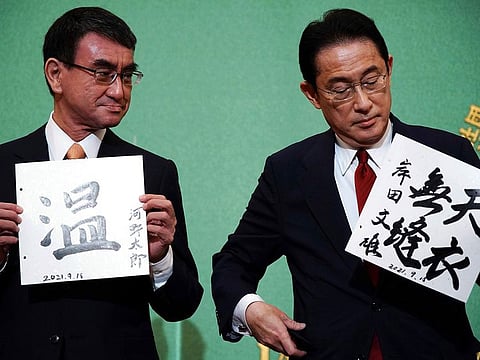 In this Sept. 18, 2021, file photo, Taro Kono, left, the cabinet minister in charge of vaccinations, and Fumio Kishida, former foreign minister, two of the four candidates for the presidential election of the ruling Liberal Democratic Party, pose with papers with their signs and words prior to a debate session hosted by the Japan National Press Club in Tokyo.