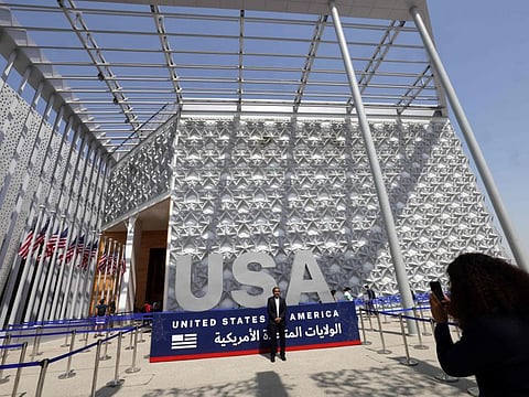 A visitor poses for a photograph in front of the USA Pavillion at Expo 2020 Dubai.