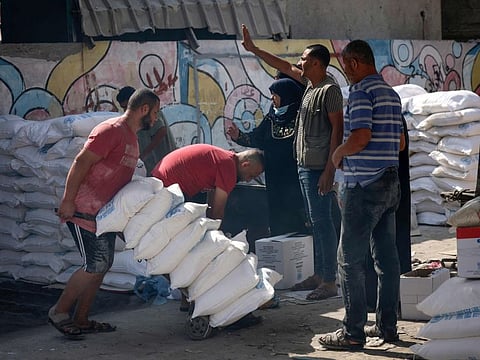 A Palestinian volunteer pushes a trolley of food rations outside an aid distribution centre run by the United Nations Relief and Works Agency (UNRWA) at the Al Shati camp for Palestinian refugees in Gaza City on October 2, 2021.
