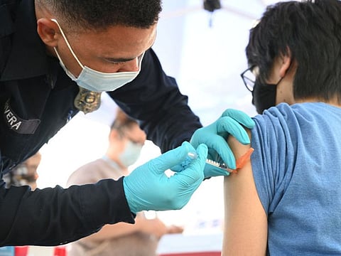 A Los Angeles County emergency medical technician, gives a second dose of Pfizer vaccine to Aaron Delgado, 16, at a pop up vaccine clinic in the Arleta neighborhood of Los Angeles.