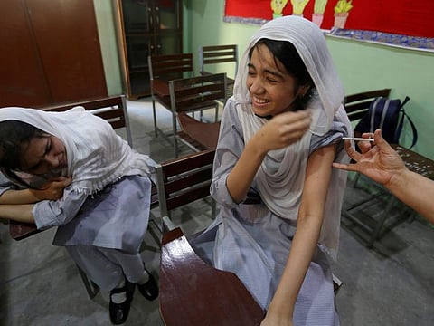 A student reacts while receiving a dose of the Pfizer COVID-19 vaccine from a health worker at a school, in Lahore, Pakistan, Saturday, Oct. 2, 2021. Pakistan government started a drive to vaccinate school children aged 12 and above to protect them from the coronavirus. AP