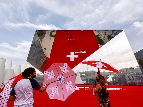 Offering the perfect selfie moment is the Switzerland Pavilion's reflective facade. Visitors play with sunbrellas as they huddle together to create a picture on the mirror