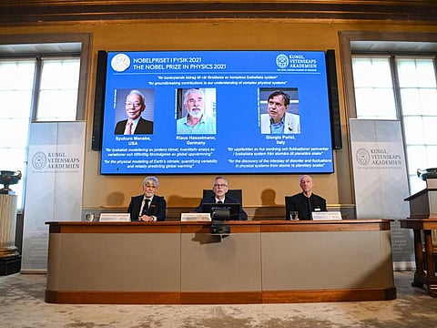Goran K. Hansson, Secretary General of the Royal Swedish Academy of Sciences, and members of the Nobel Committee for Physics Thors Hans Hansson (left) and John Wettlaufer sit in front of a screen displaying the co-winners of the 2021 Nobel Prize in Physics from left: Syukuro Manabe (US-Japan), Klaus Hasselmann (Germany) and Giorgio Parisi (Italy) at the Royal Swedish Academy of Sciences in Stockholm, Sweden, on October 5, 2021.