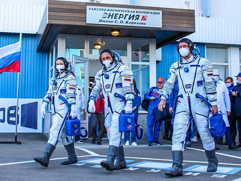 This handout photo taken and released on October 5, 2021 by Russian Space Agency Roscosmos crew members, cosmonaut Anton Shkaplerov (centre), actress Yulia Peresild (left) and film director Klim Shipenko walking to board the Soyuz MS-19 spacecraft prior to its launch at the Russian-leased Baikonur cosmodrome.