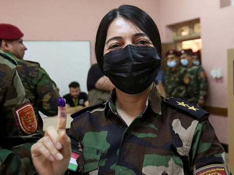 A member of Kurdish Peshmerga military forces shows her ink stained finger after voting inside a polling station, two days ahead of Iraq's parliamentary elections in a special process, in Arbil, Iraq, on October 8, 2021.