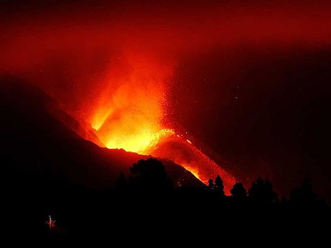 A view of the volcano that continues to spew out lava on the Canary island of La Palma, Spain in the early hours of Sunday, Oct. 10, 2021. A new river of lava has belched out from the La Palma volcano, spreading more destruction on the Atlantic Ocean island where molten rock streams have already engulfed over 1,000 buildings.