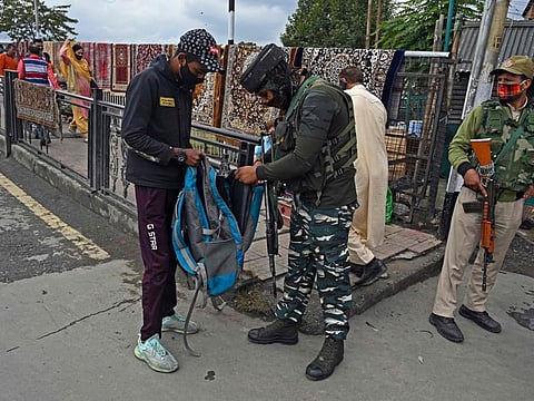 A security personnel checks the bag of a pedestrian along a street in Srinagar on October 11, 2021, as militants shot dead five soldiers in Indian-administered Kashmir.